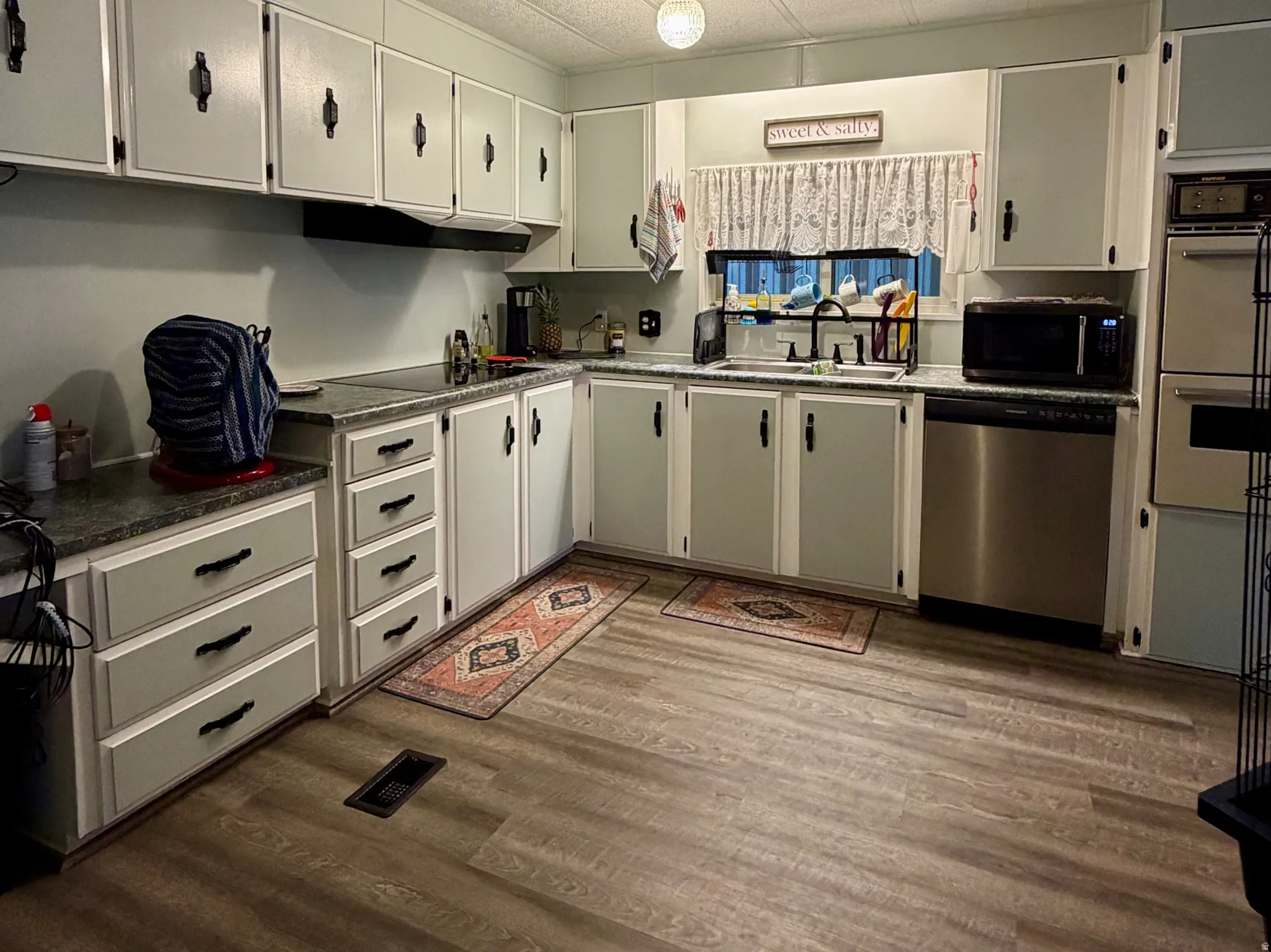 Kitchen featuring laminate wood-finish flooring, a stainless steel dishwasher, and a built-in oven