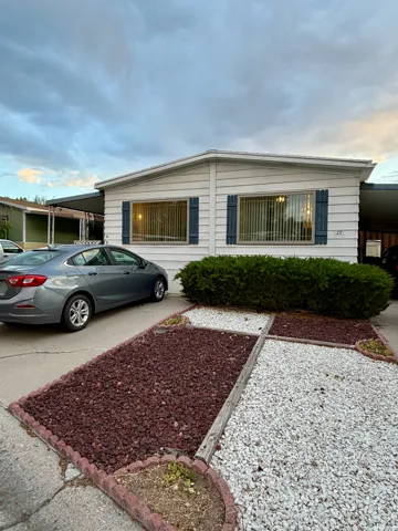 White siding exterior with blue window shutters, featuring a covered 2 car tandem carport