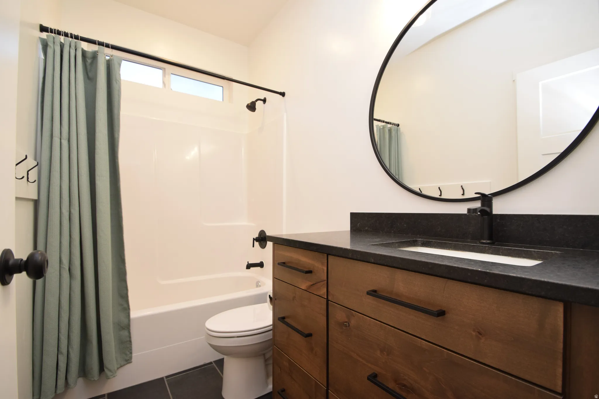 Bathroom featuring a wood-finish vanity with drawer storage, dark countertop, and integrated sink
