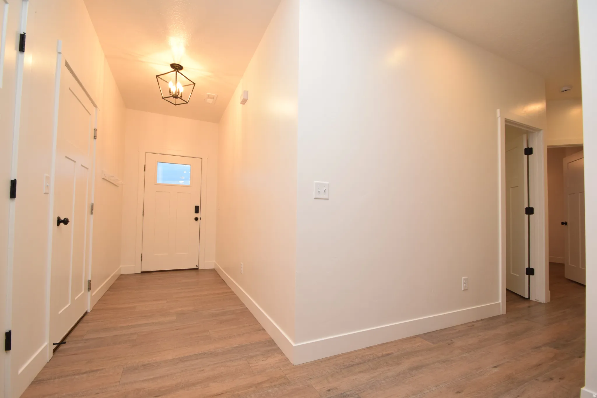 Entryway featuring light wood-finish flooring, white walls, and a contemporary geometric ceiling light fixture