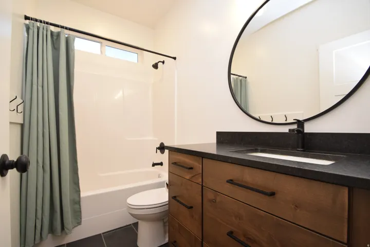 Bathroom featuring a wood-finish vanity with drawer storage, dark countertop, and integrated sink