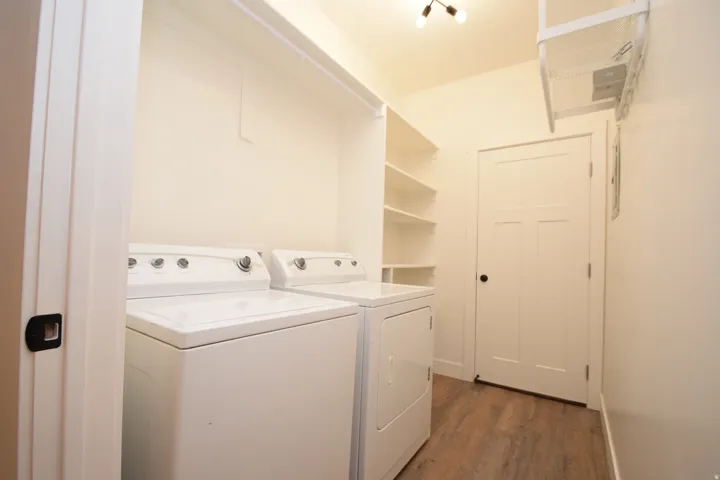 Dedicated laundry area featuring a washer and dryer, built-in shelving, wood-finish flooring, and recessed lighting