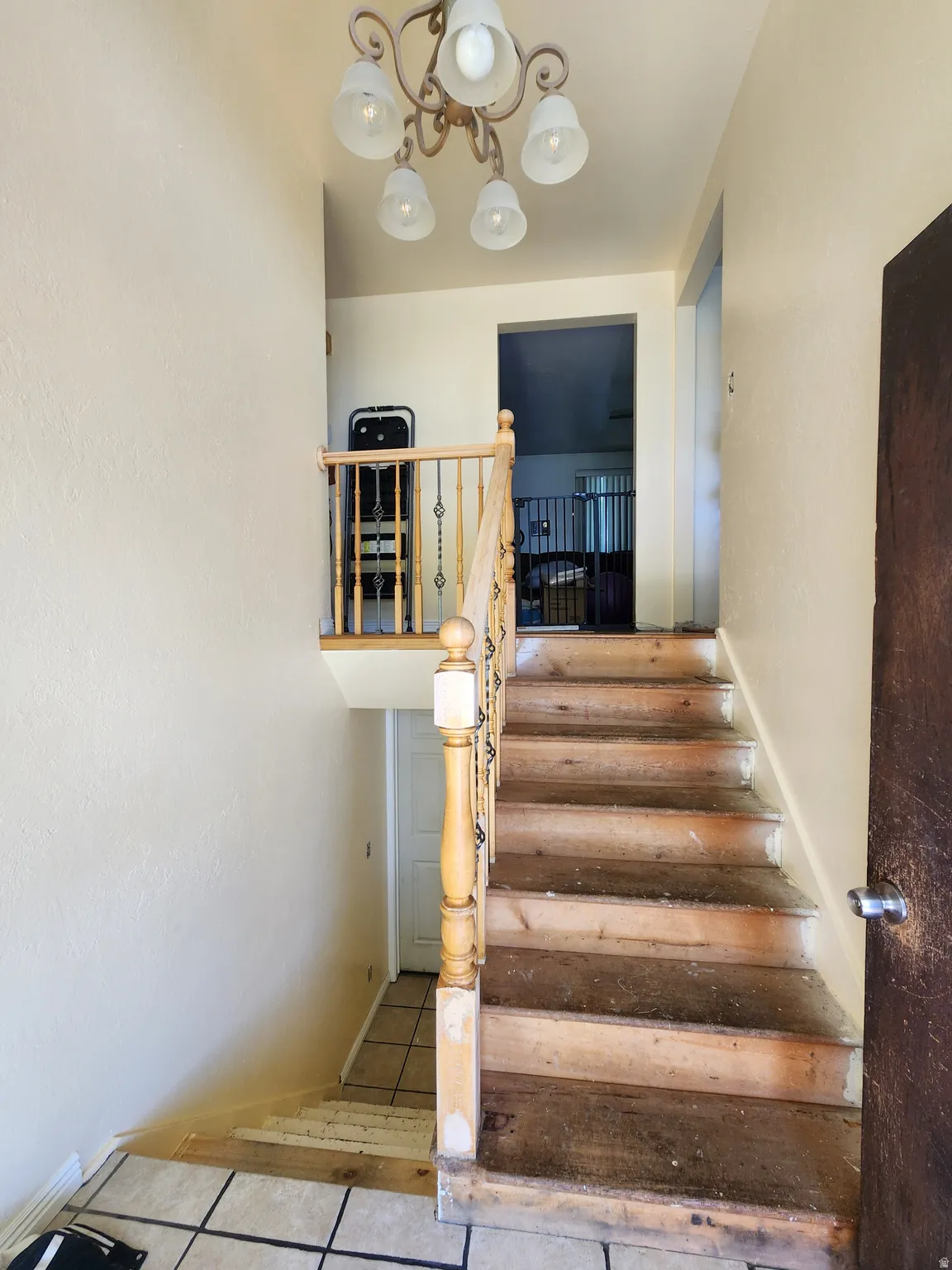 Staircase with wood newel post and balusters, featuring a decorative five-light chandelier