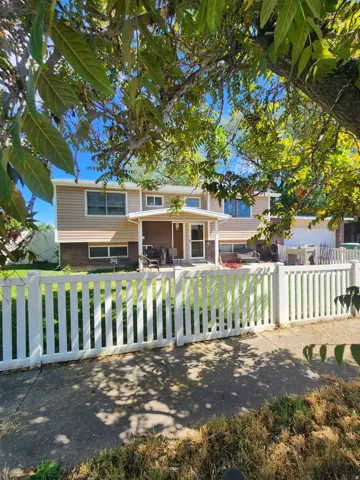 Split-level residence featuring a covered front porch and a white picket fence