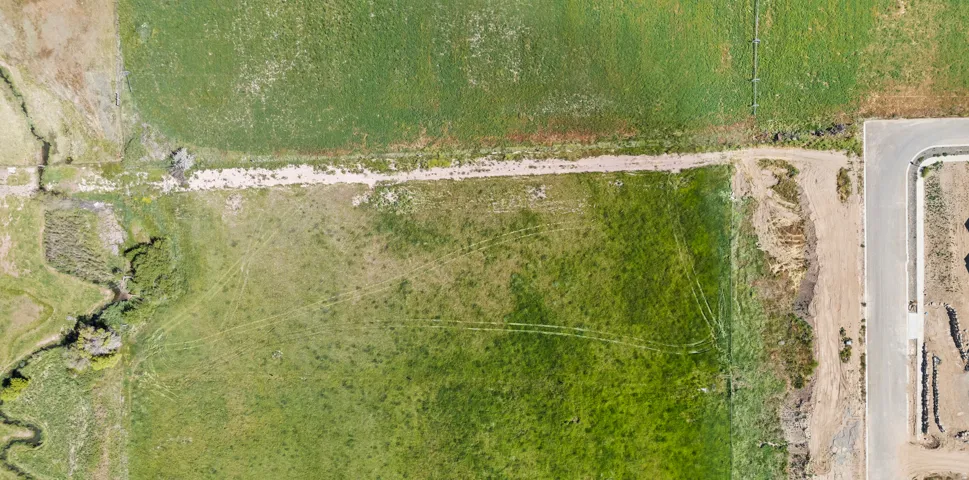 Expansive land parcel featuring natural grass areas and partial paved road frontage