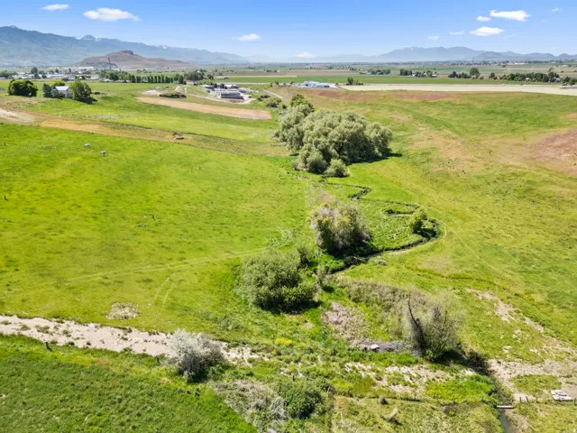 Expansive green fields featuring a winding stream and scattered mature trees