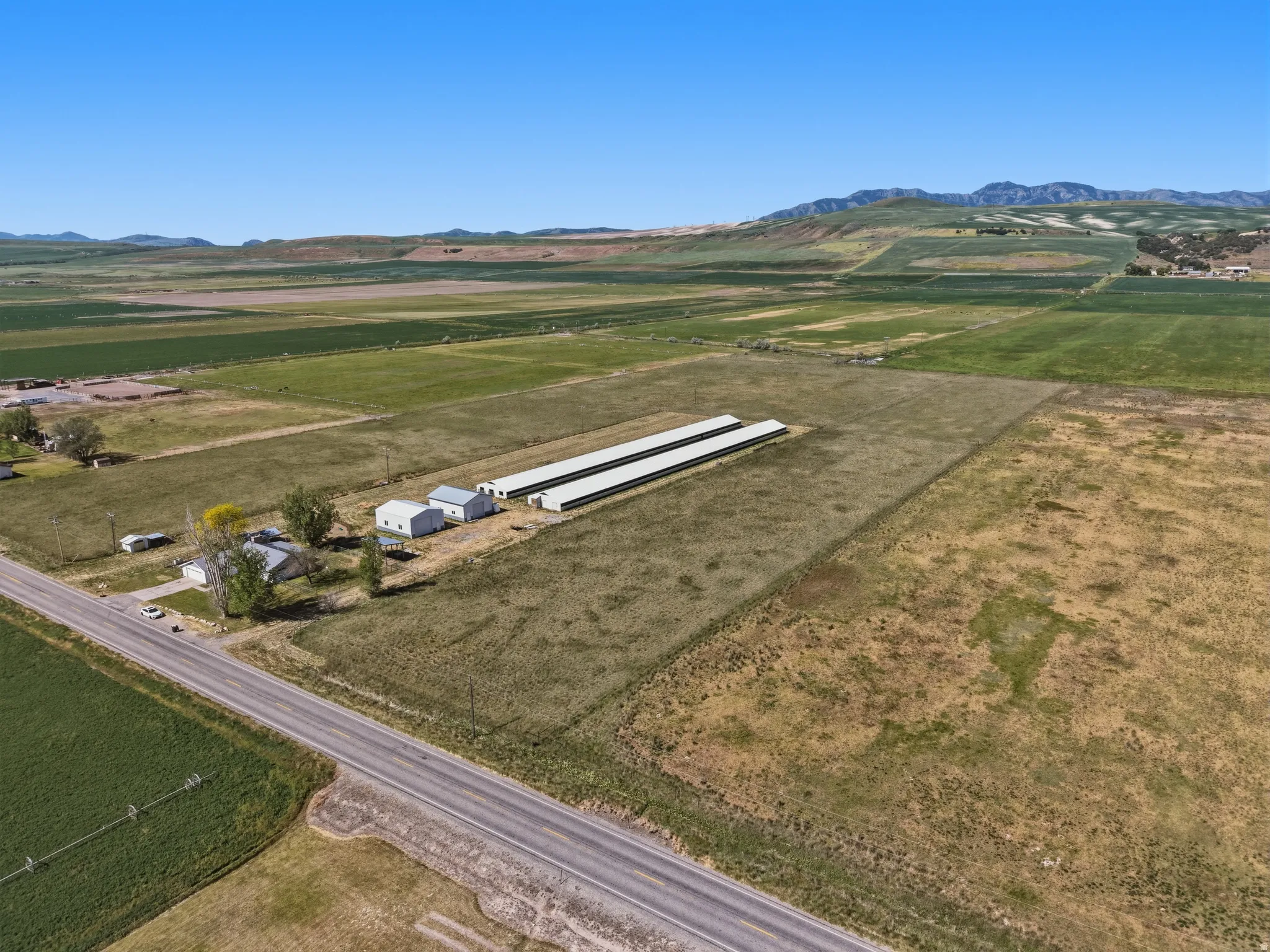 Aerial perspective showcasing multiple agricultural buildings and a main residence set against a mountainous backdrop
