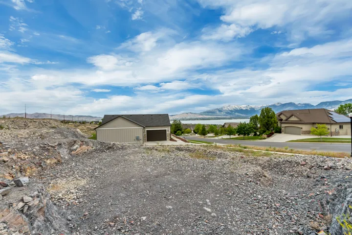 Expansive graded lot featuring a gravel surface, visible rock formations, and a clear sky overhead