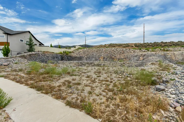 Excavated residential lot featuring a concrete sidewalk and natural rock formations
