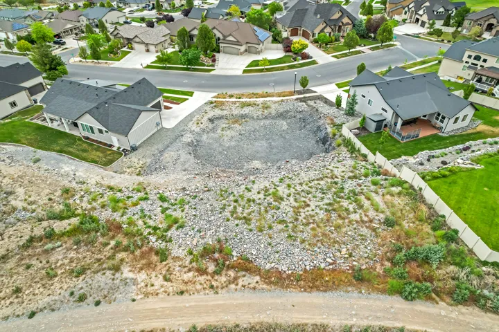 Residential building lot featuring an excavated foundation, surrounded by existing homes