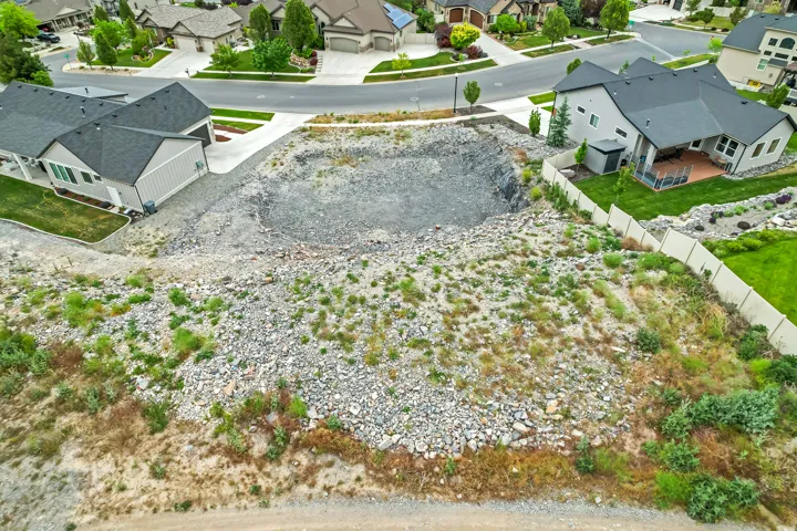 Expansive undeveloped lot featuring a large excavated area, surrounded by established residential properties