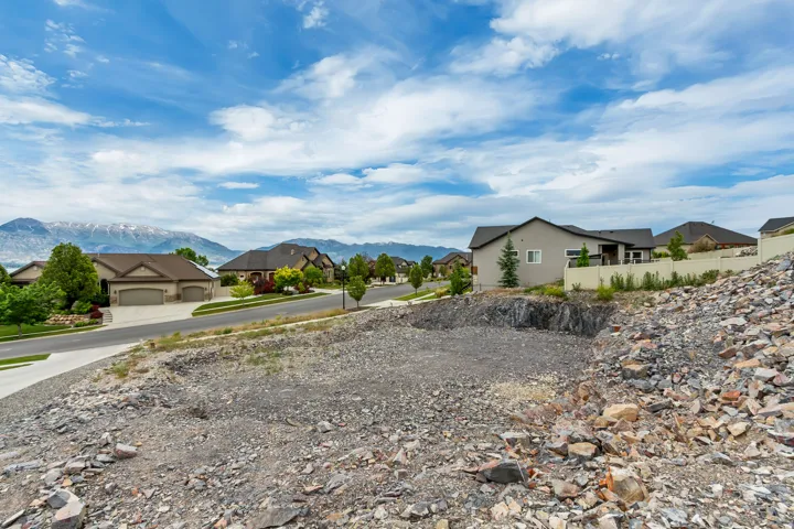 Graded lot featuring a rocky terrain, a paved street, and distant mountain scenery