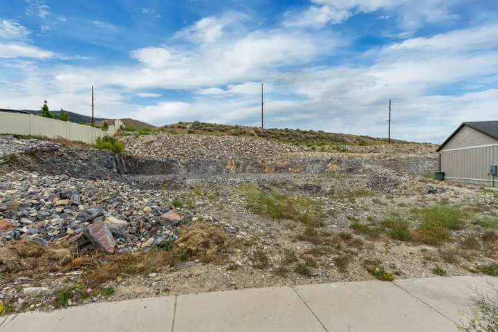 Terraced land lot featuring a graded building pad, a concrete sidewalk, and a partial privacy fence