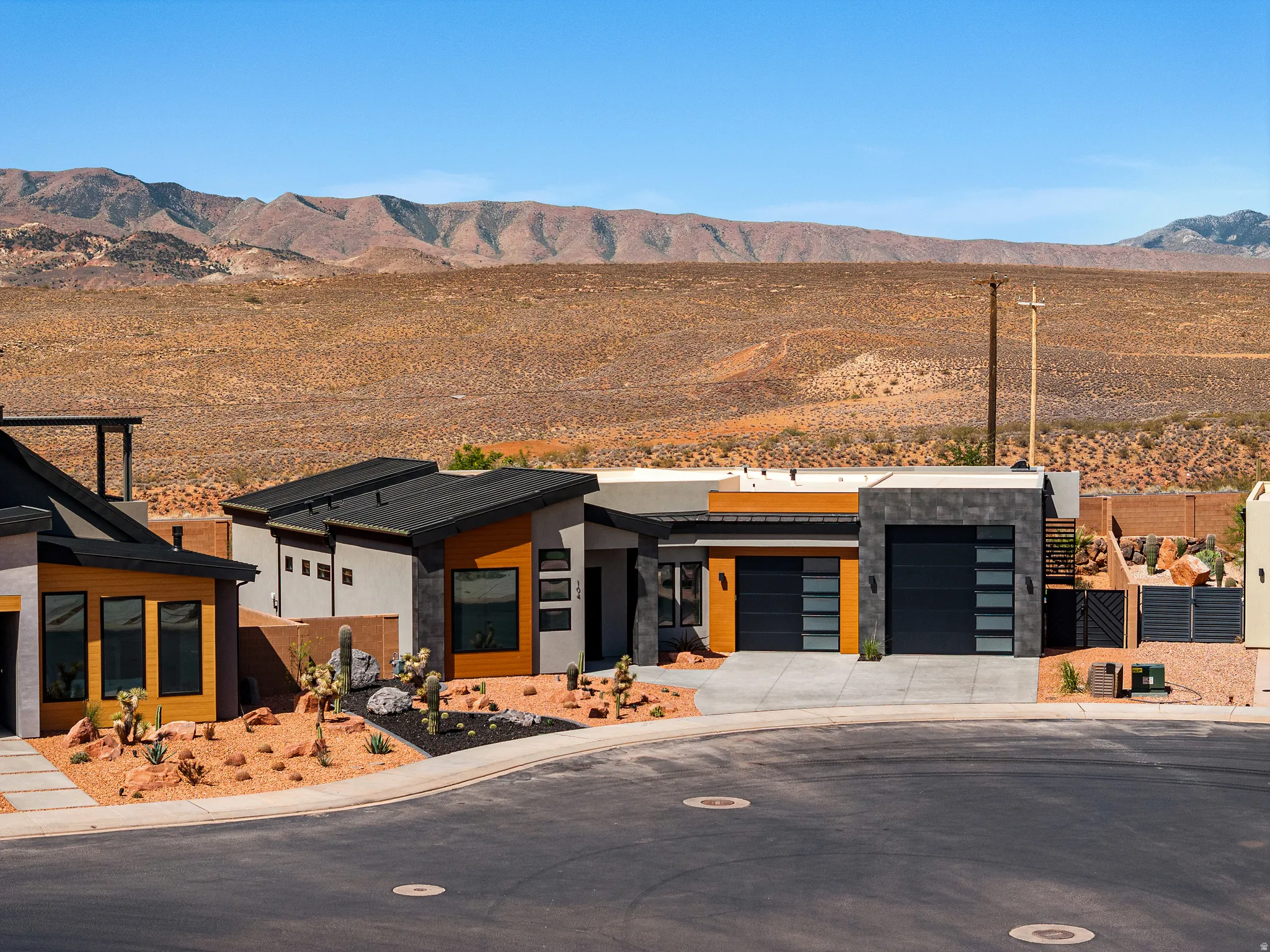 Modern desert architecture featuring a flat roofline, integrated two-car garage with frosted panels, and a desert-adapted landscaping