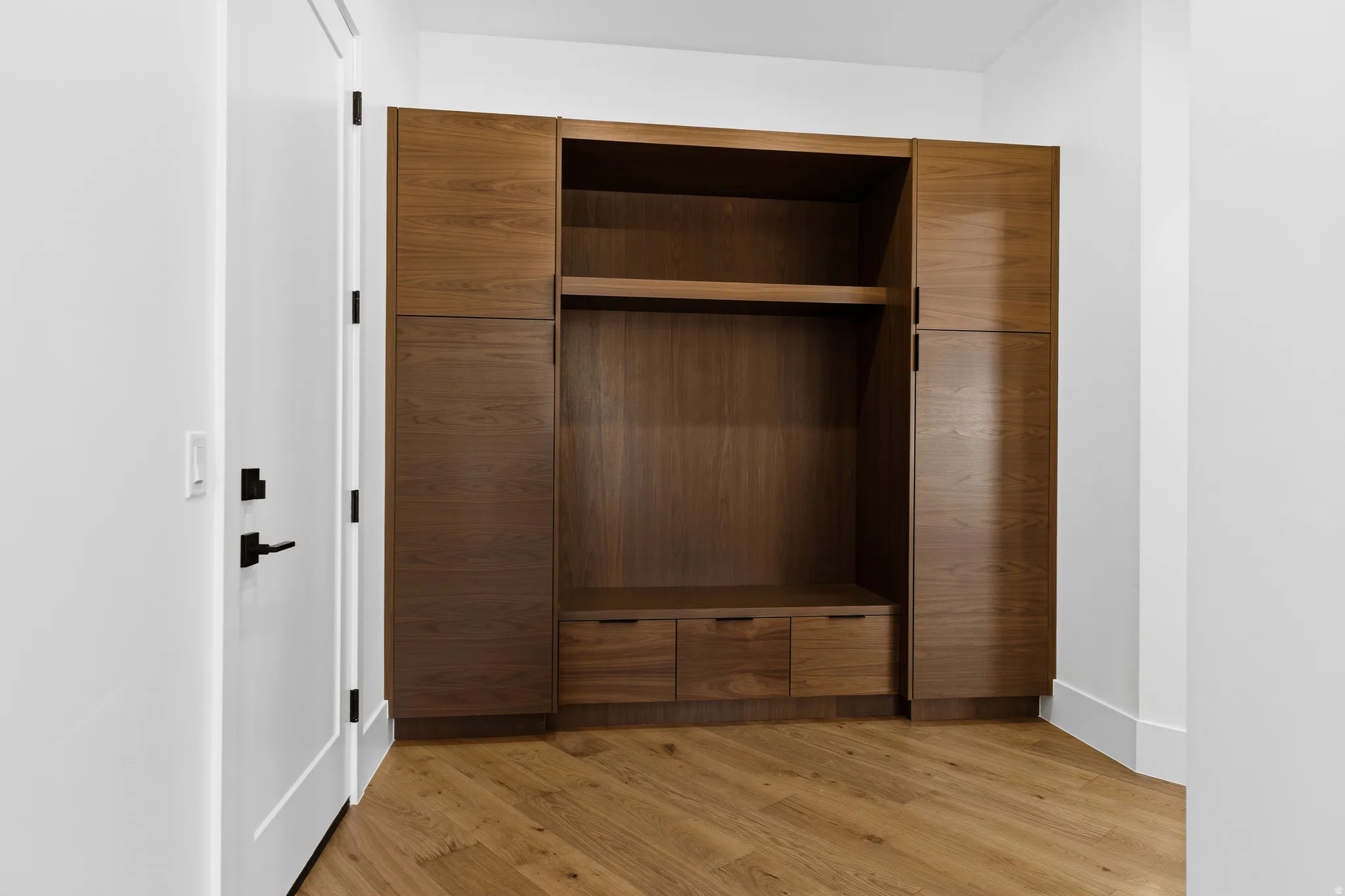 Built-in wood-finish cabinetry featuring open shelving, multiple drawers, and ample enclosed storage