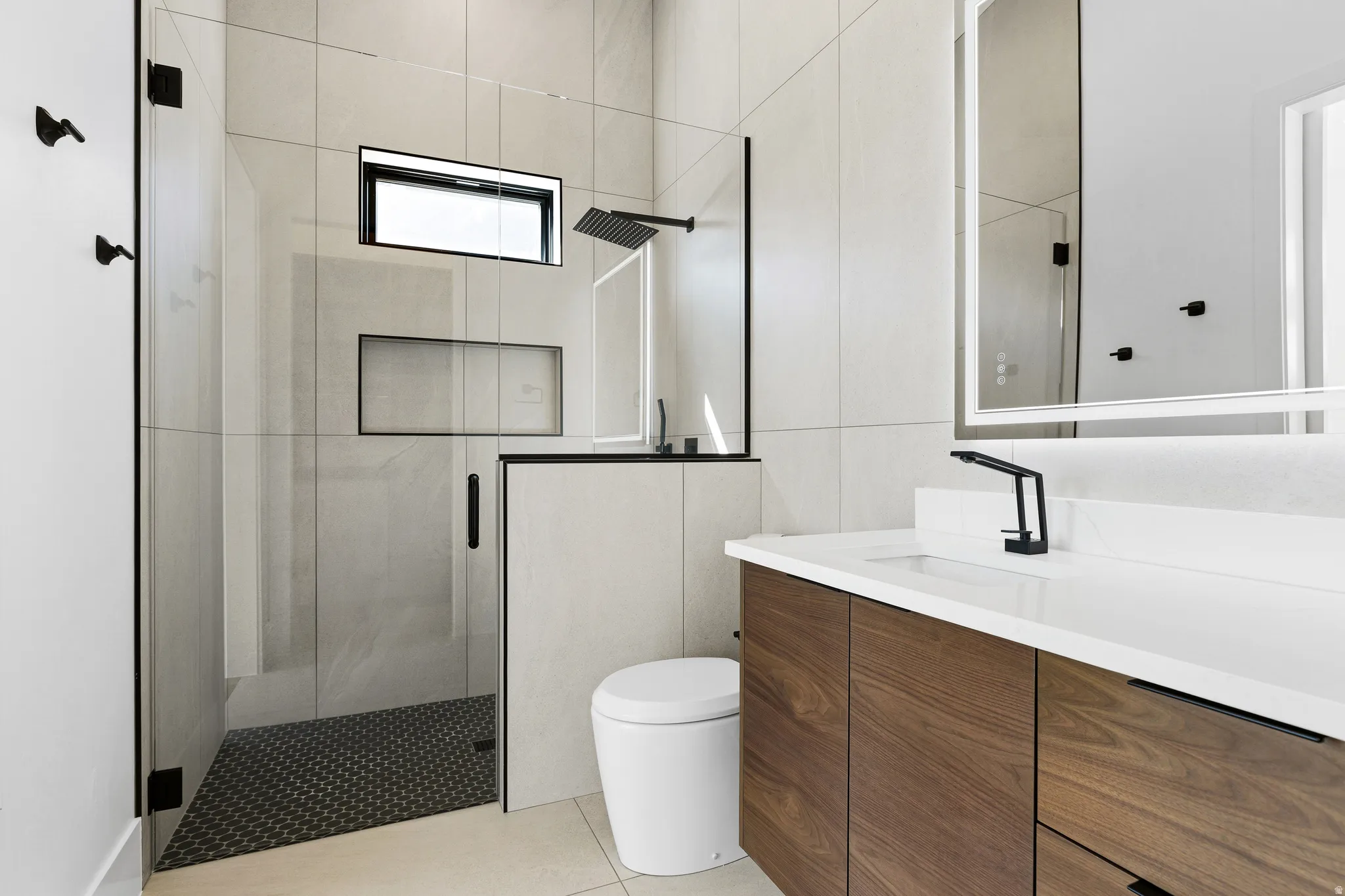 Contemporary bathroom featuring a spacious glass-enclosed shower with black-framed accents, a rain showerhead, and an integrated niche