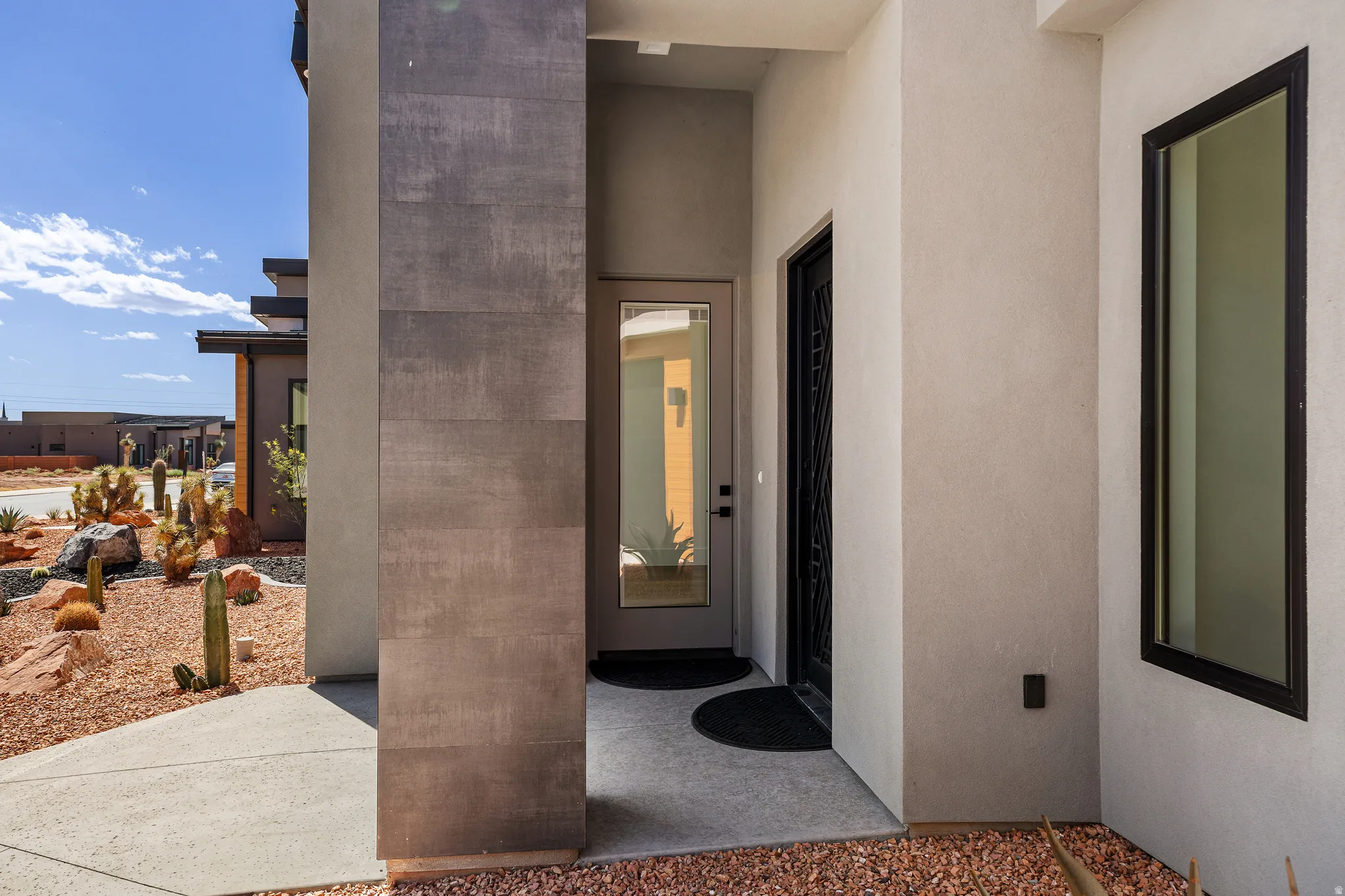 Modern entry featuring a textured stone-clad column and stucco exterior