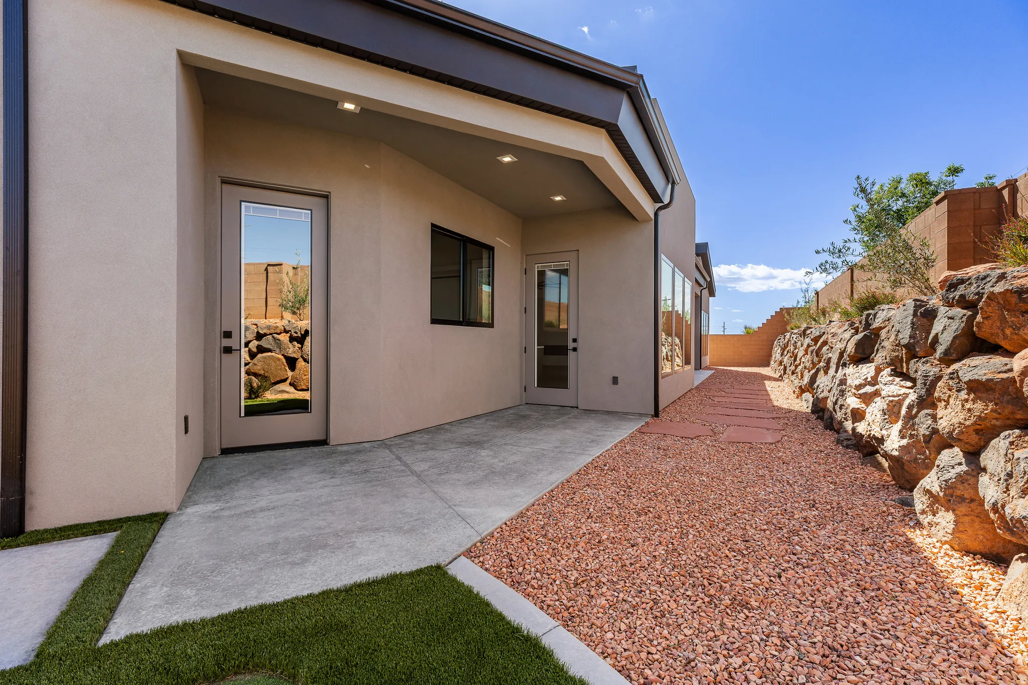 Rear exterior with covered patio, stucco finish, and modern glass-paneled doors
