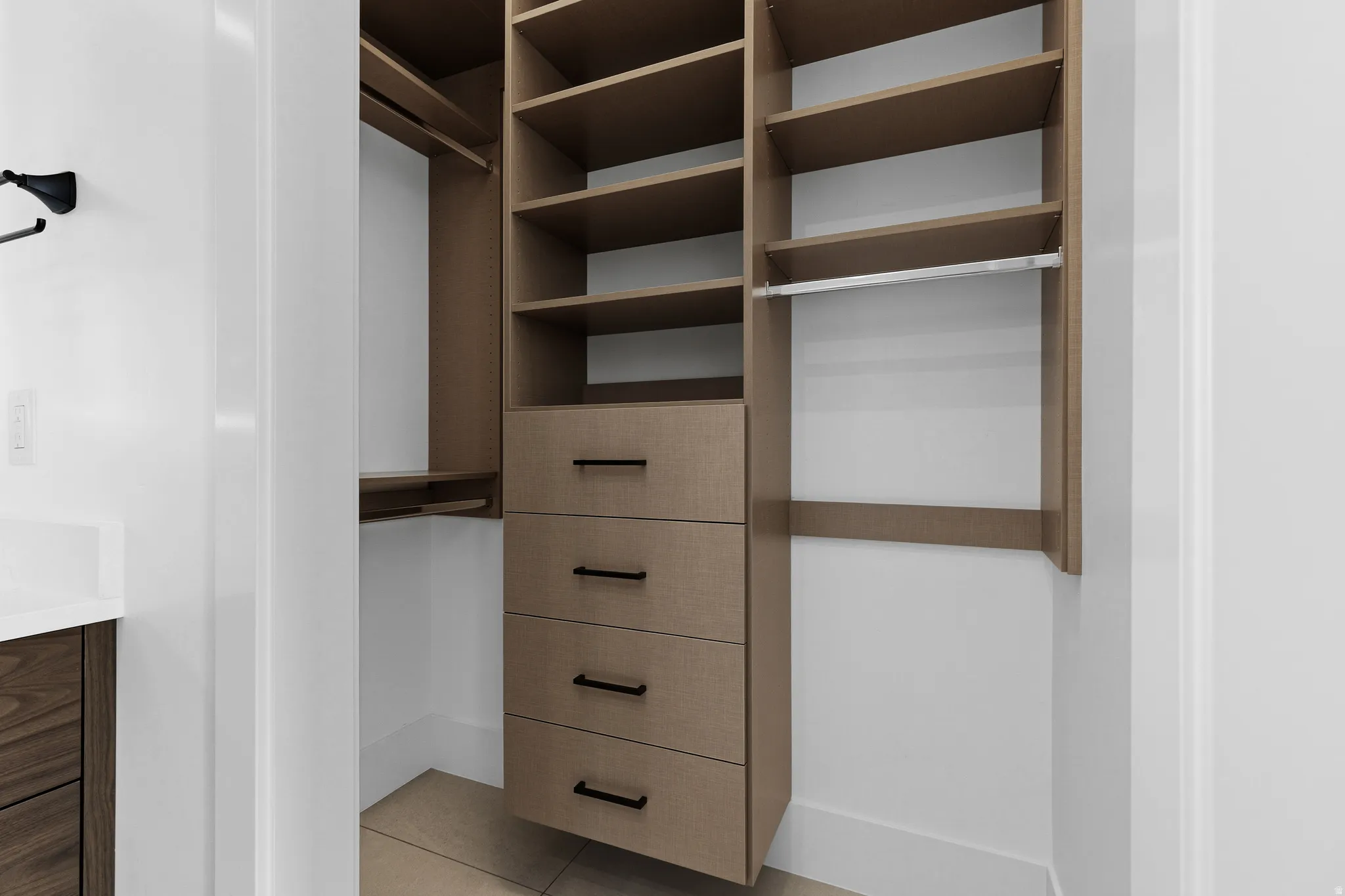Custom built-in closet system featuring multiple shelves, integrated drawers with black hardware, and hanging rods