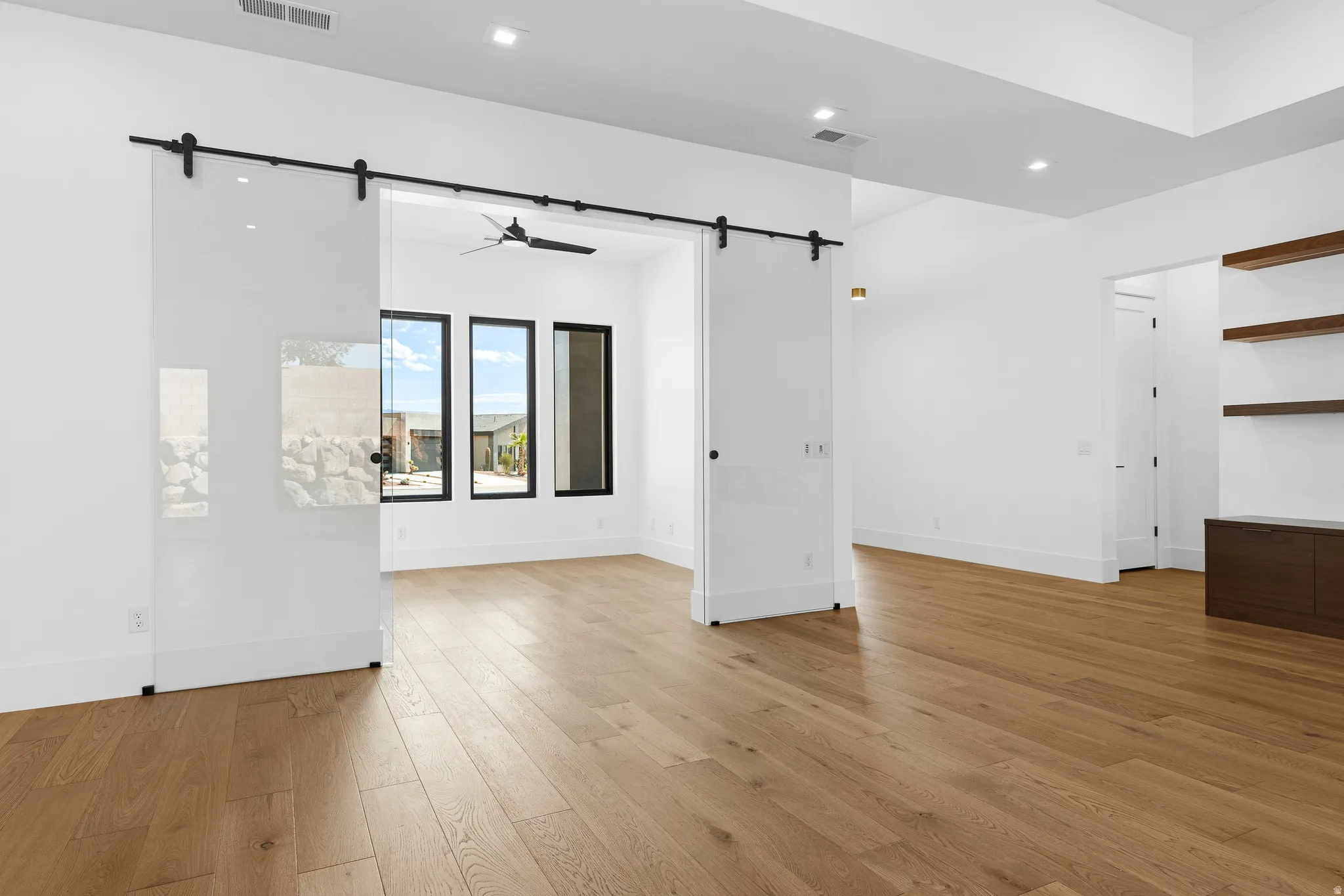 Wide plank wood-finish flooring extending into a bright interior space with glass barn doors