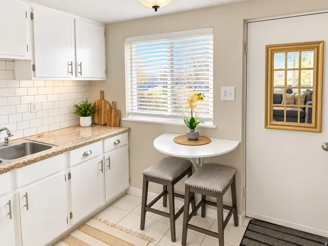 White cabinetry, subway tile backsplash, granite-style countertops, stainless steel sink, and a built-in folding table