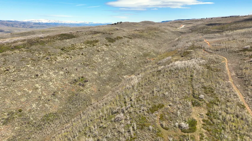 Expansive undeveloped terrain featuring varied topography, natural vegetation, and a visible dirt road