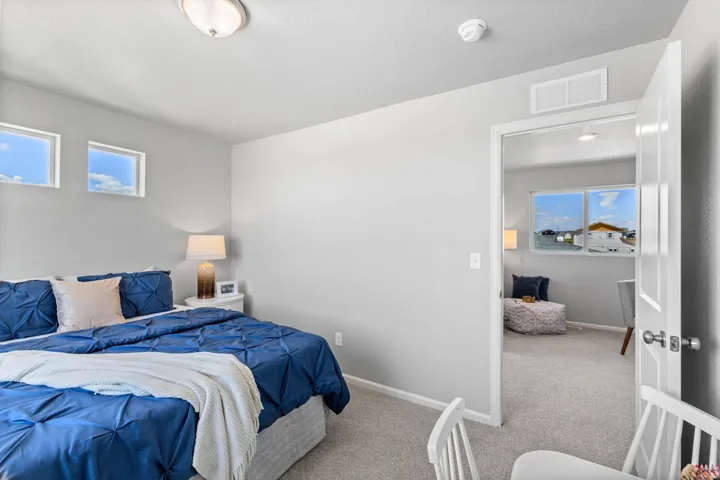 Carpeted bedroom featuring two high transom windows providing natural light