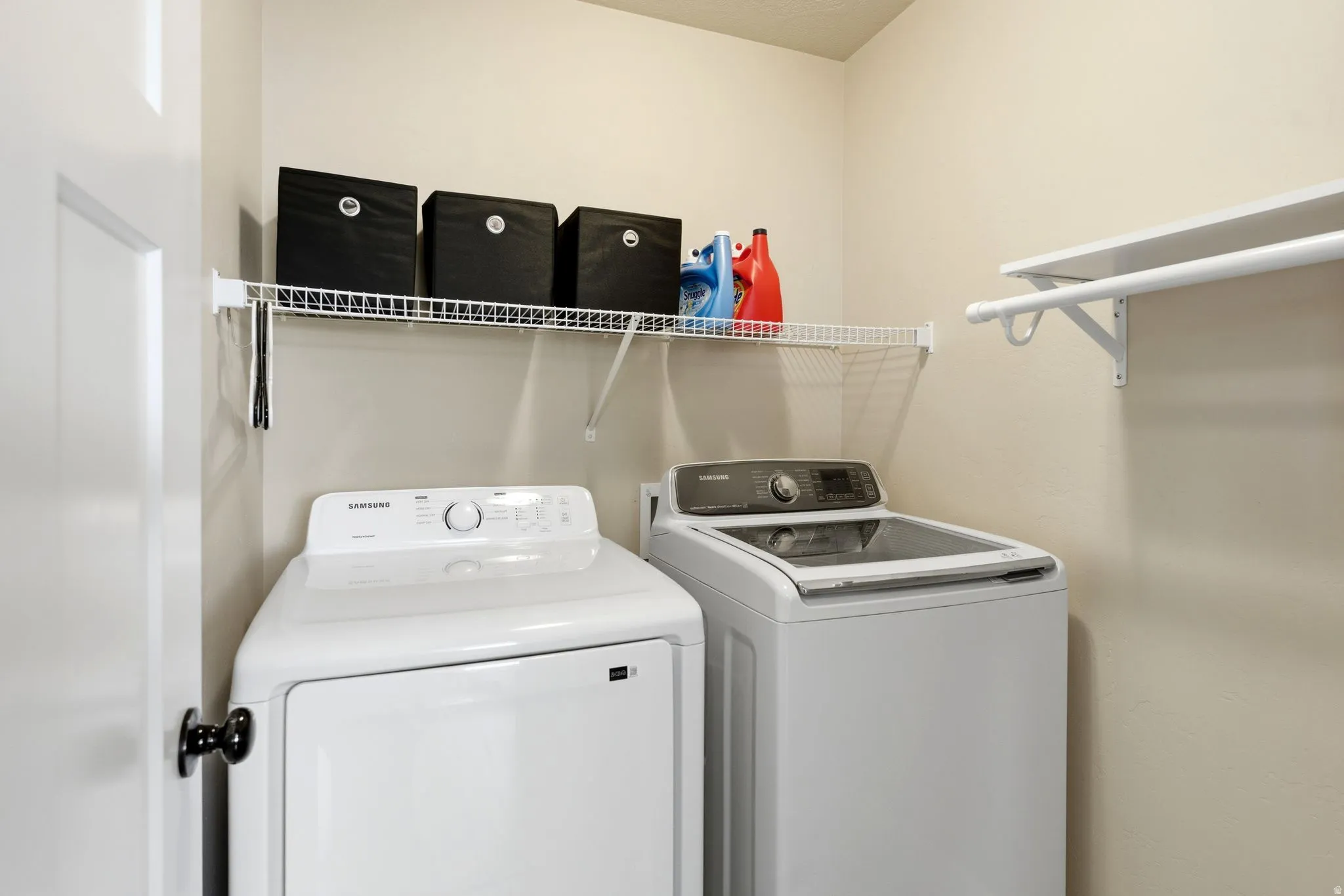 Dedicated laundry area featuring a white wire shelving unit, a white clothing rod, and neutral wall paint