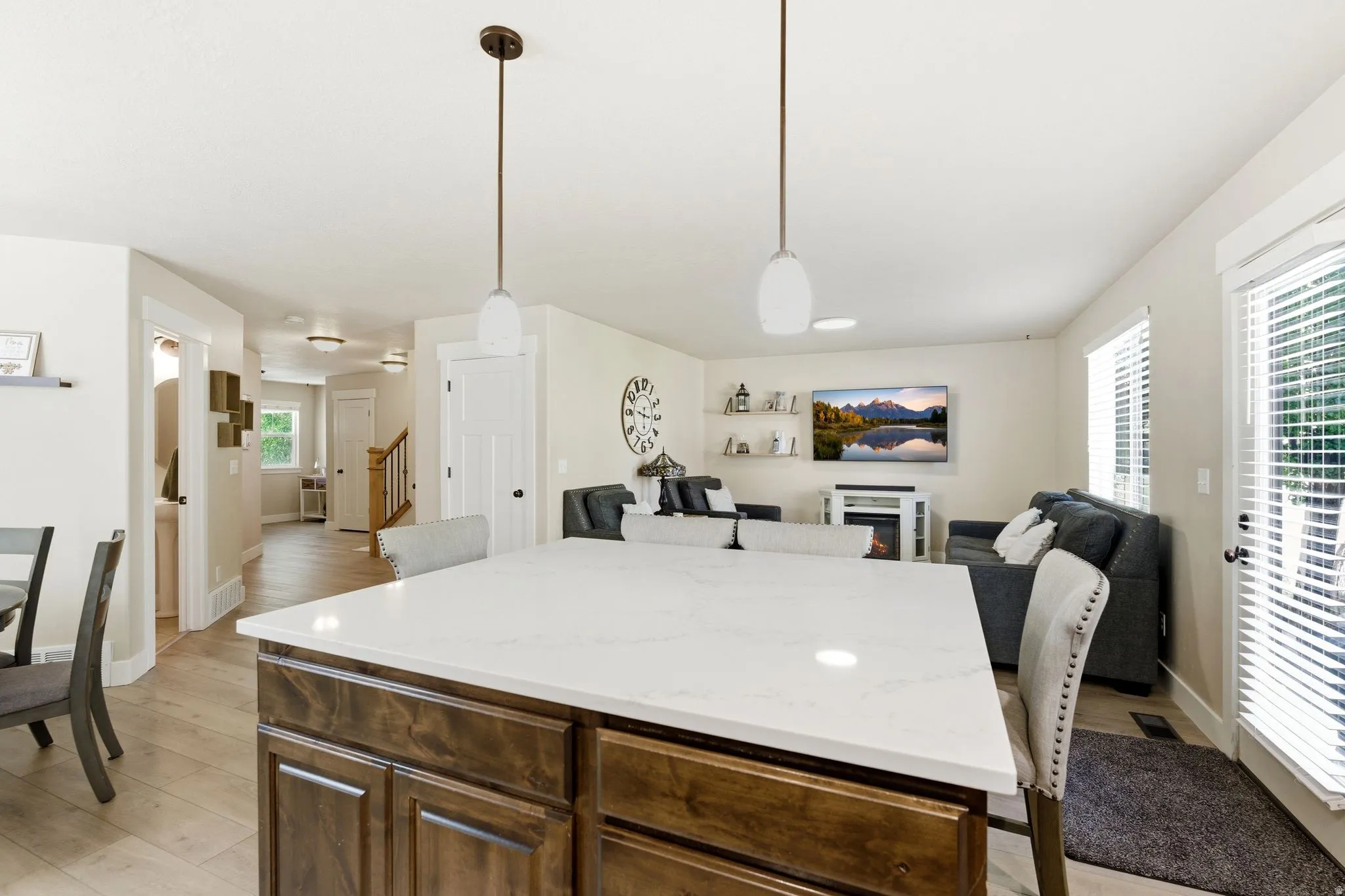 Kitchen island featuring a light-toned countertop, dark wood-finish cabinetry, and pendant lighting