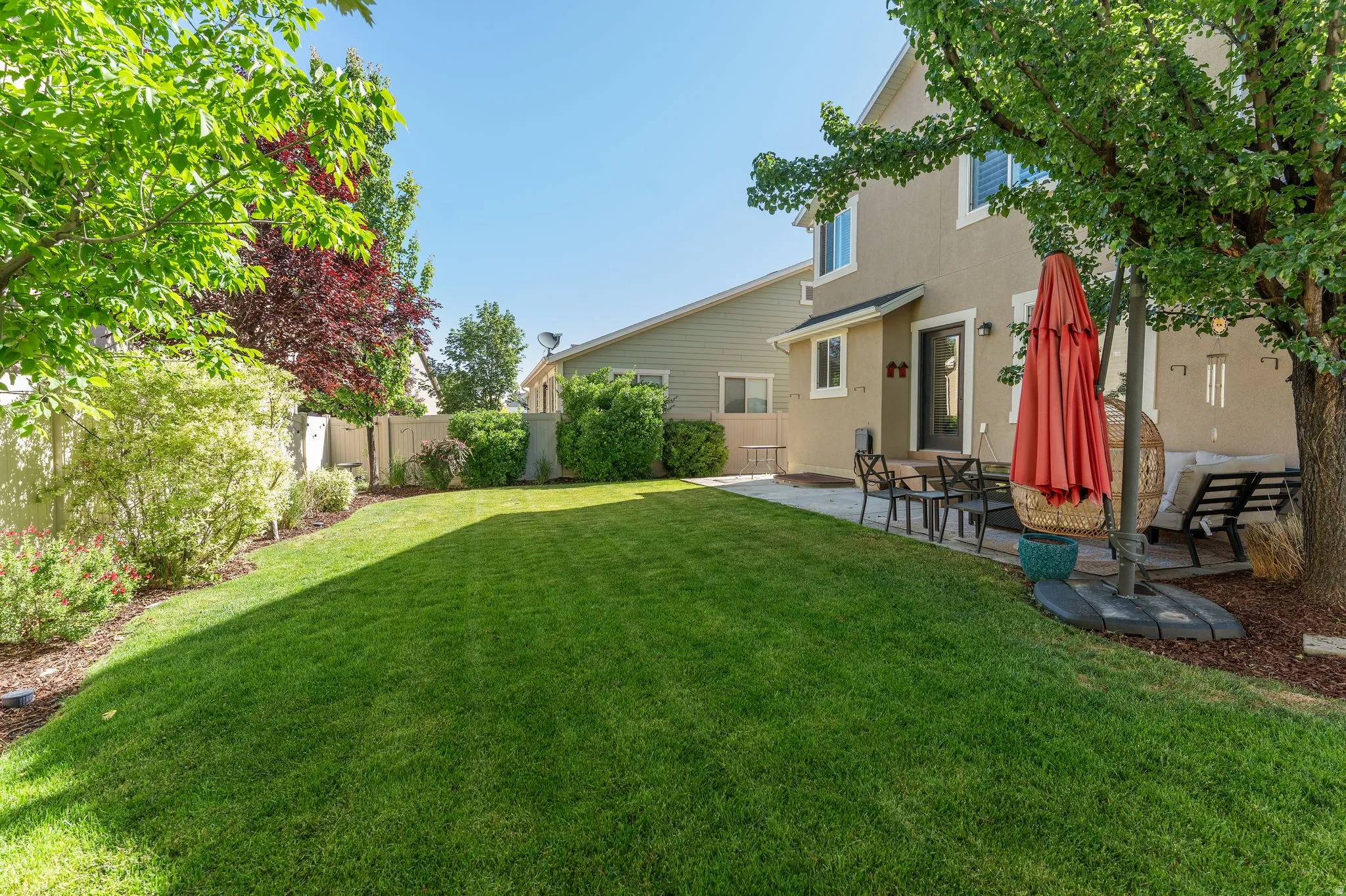 Expansive rear yard featuring a large lawn area, mature trees, and shrubs