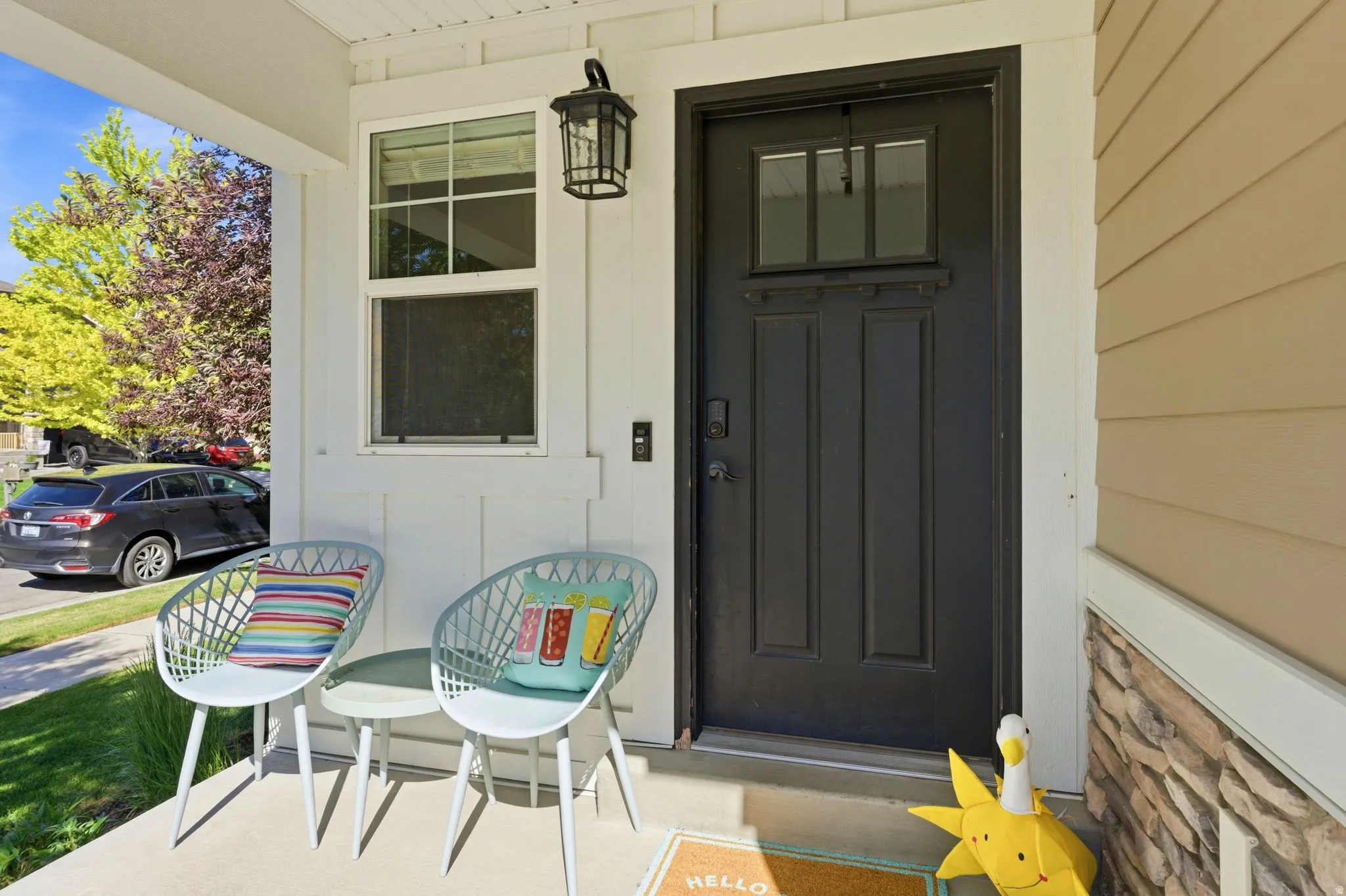 Covered front porch featuring a black paneled door with glass inserts, an exterior wall lantern, and a doorbell system