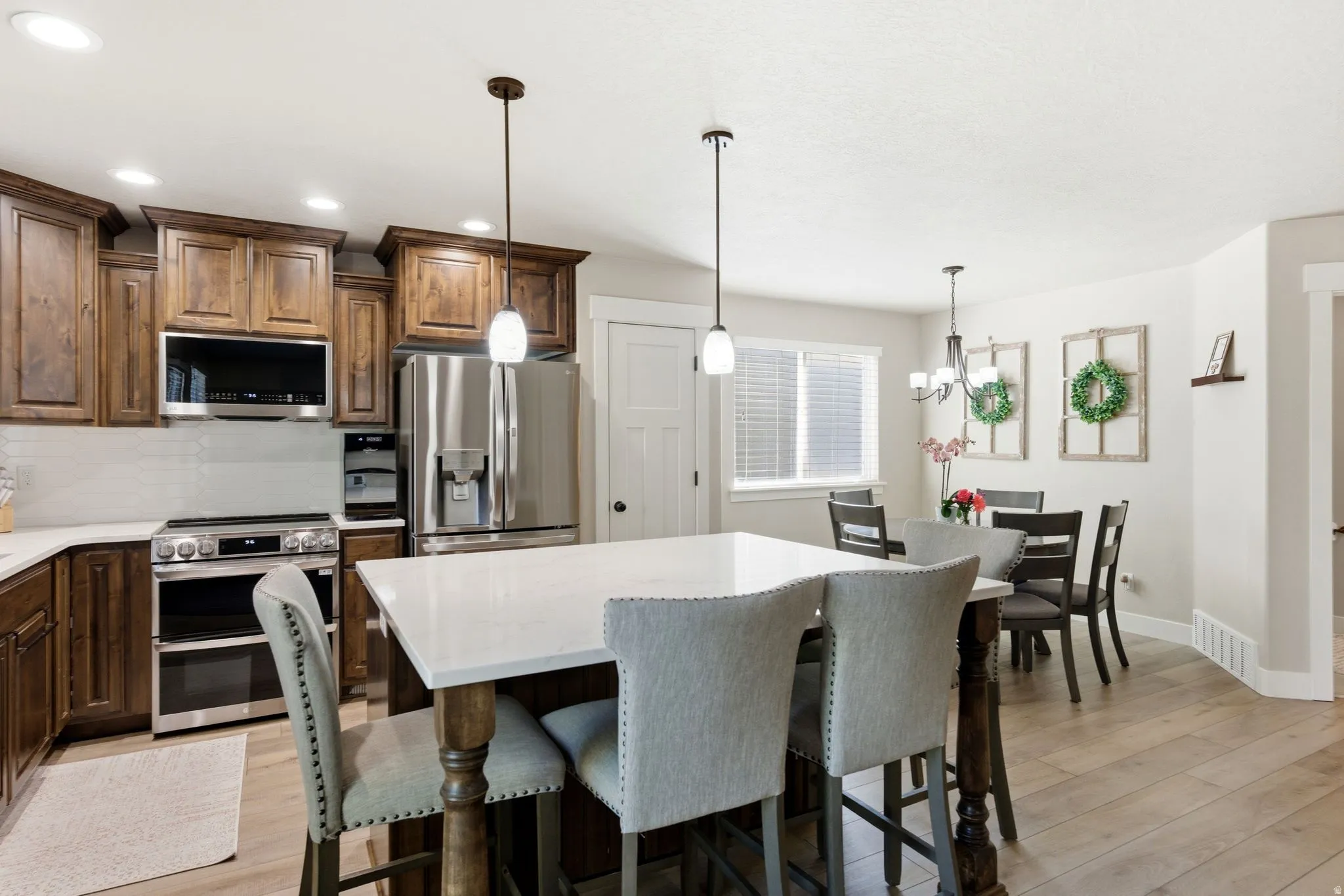 Kitchen featuring a large island with white countertop, dark wood cabinetry, stainless steel appliances, and wood-finish flooring
