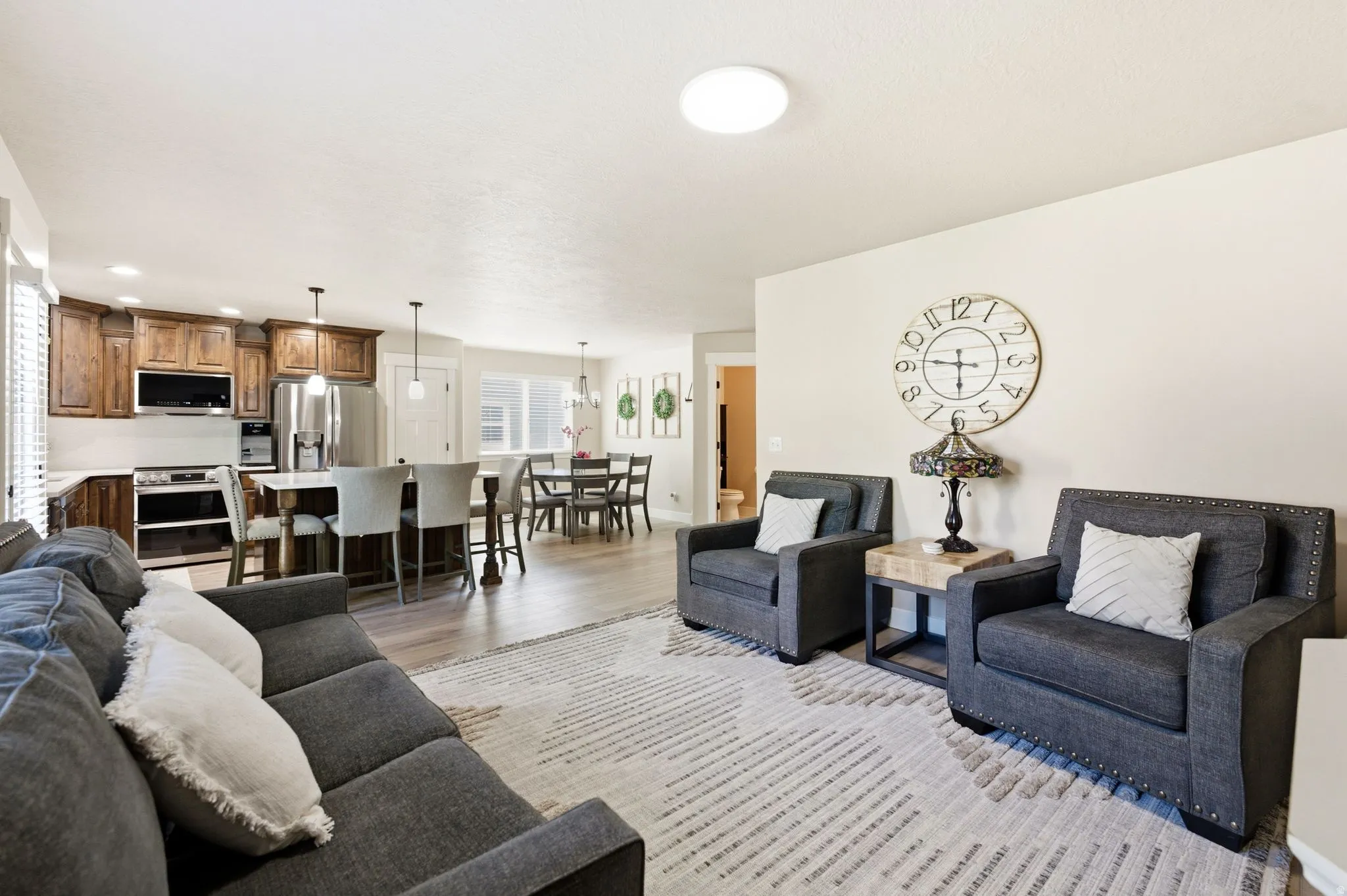 Open-concept living space featuring wood-finish flooring, a kitchen island with seating, pendant lighting, and recessed lighting