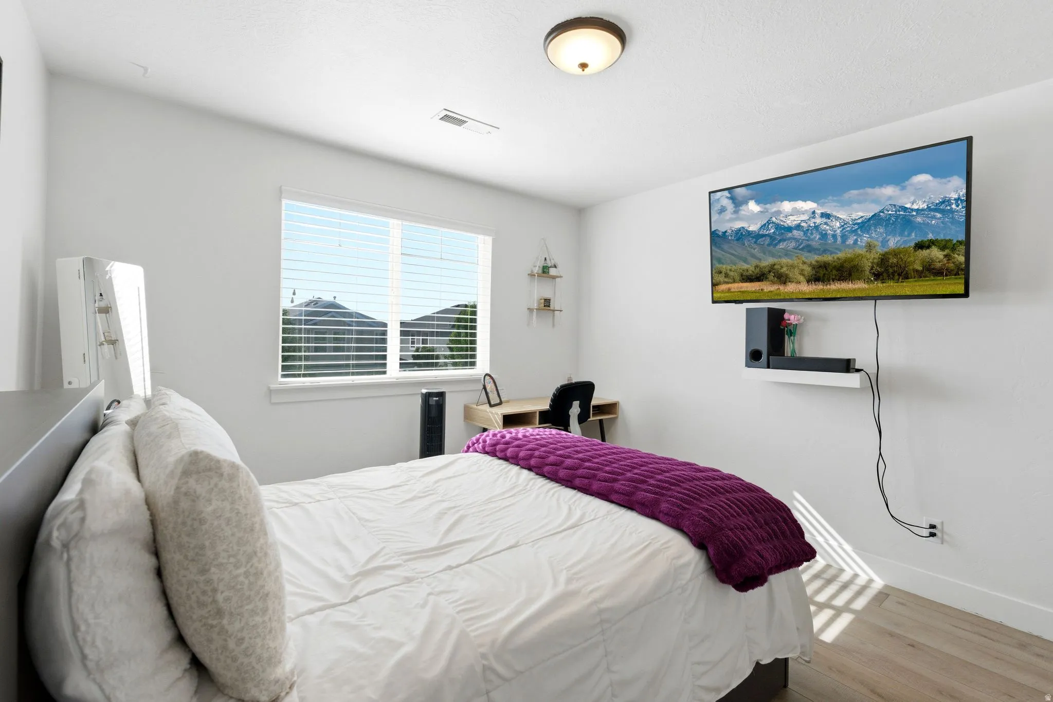 Bedroom featuring wood-finish flooring, a ceiling-mounted light fixture, and a window with blinds