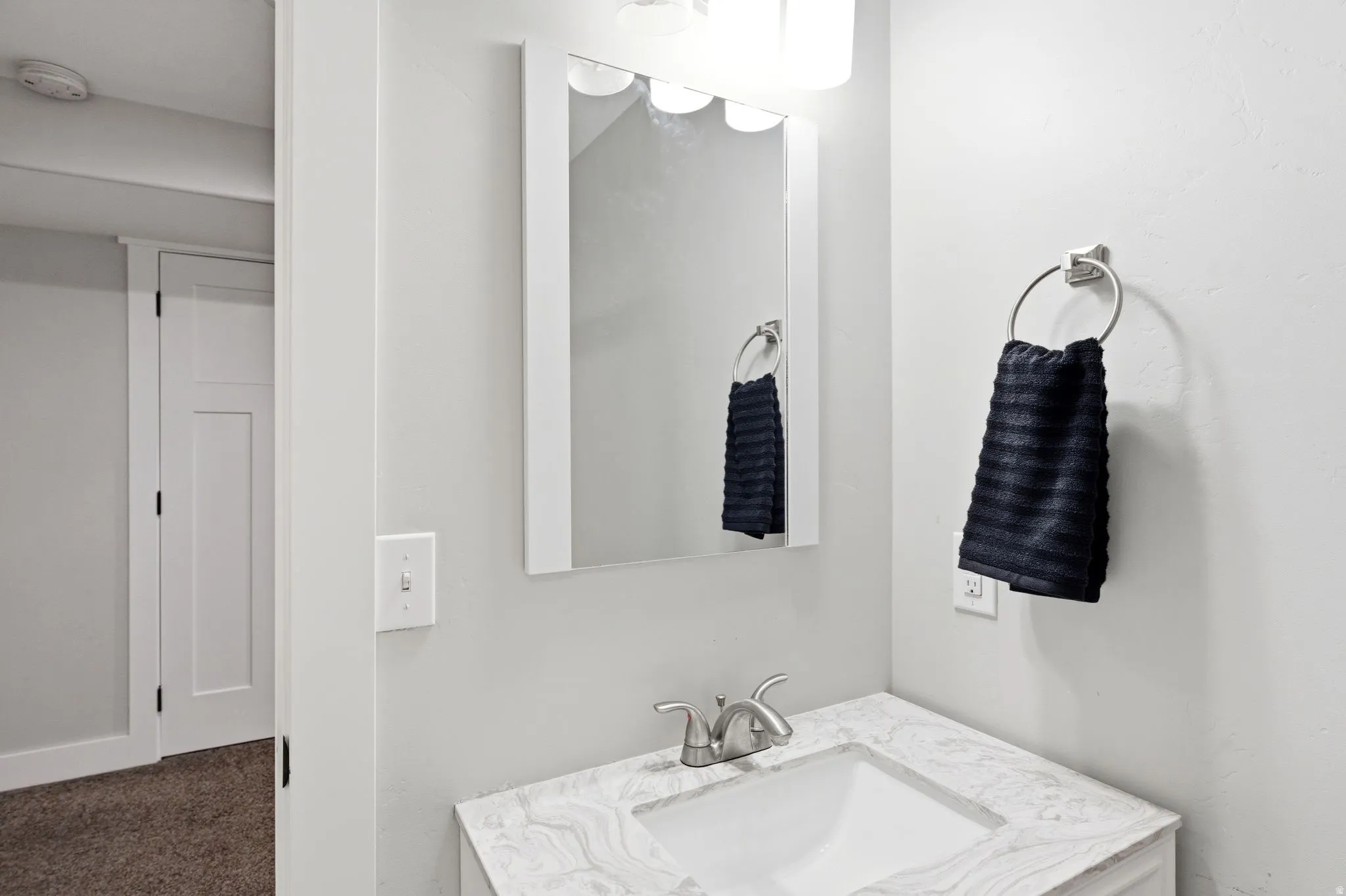 Bathroom vanity featuring a rectangular undermount sink, a marble-patterned countertop, and a chrome-finish faucet