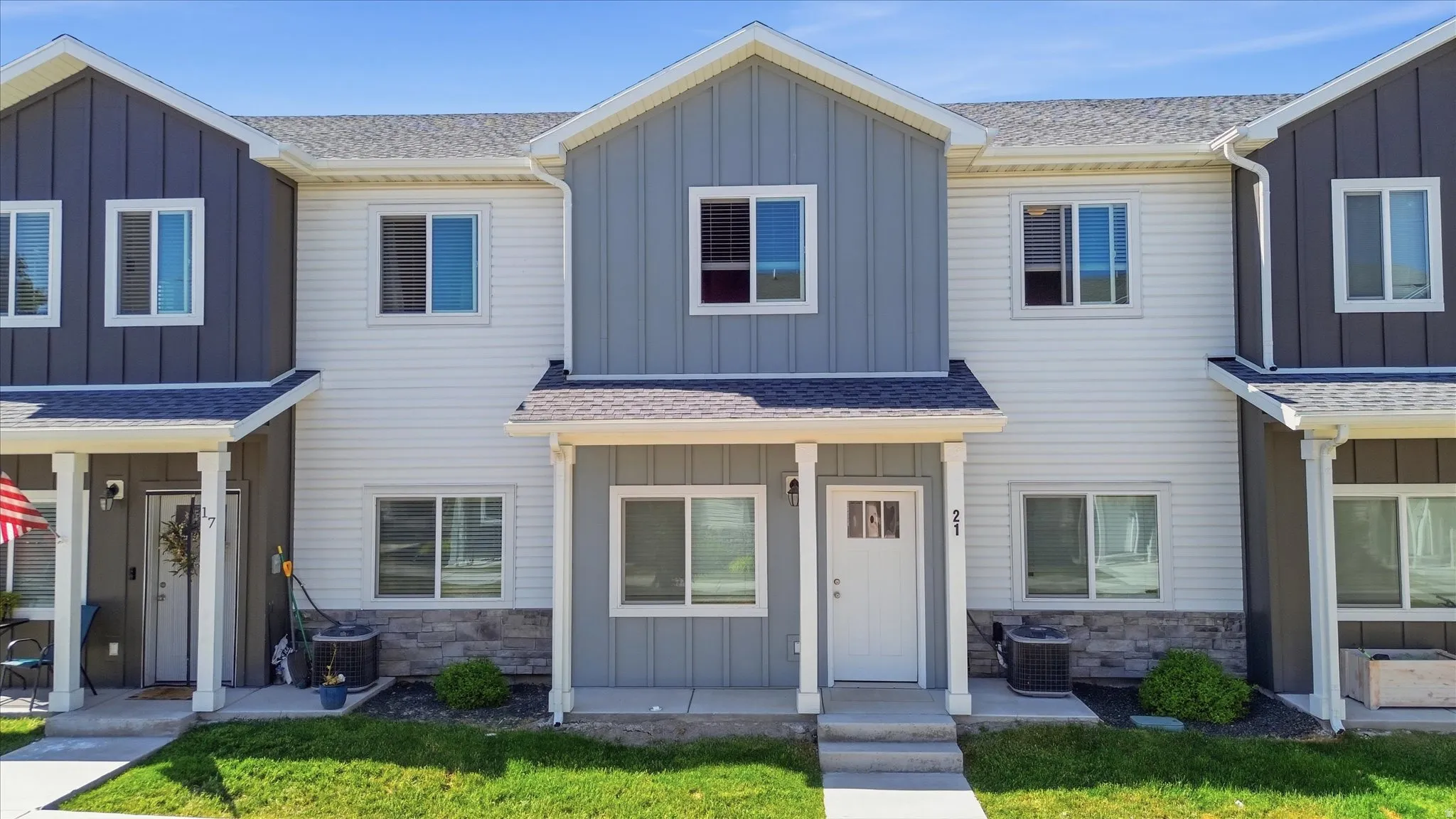 Townhome exterior featuring a contrasting color palette, board and batten siding, horizontal siding, stone veneer accents, and a covered entry
