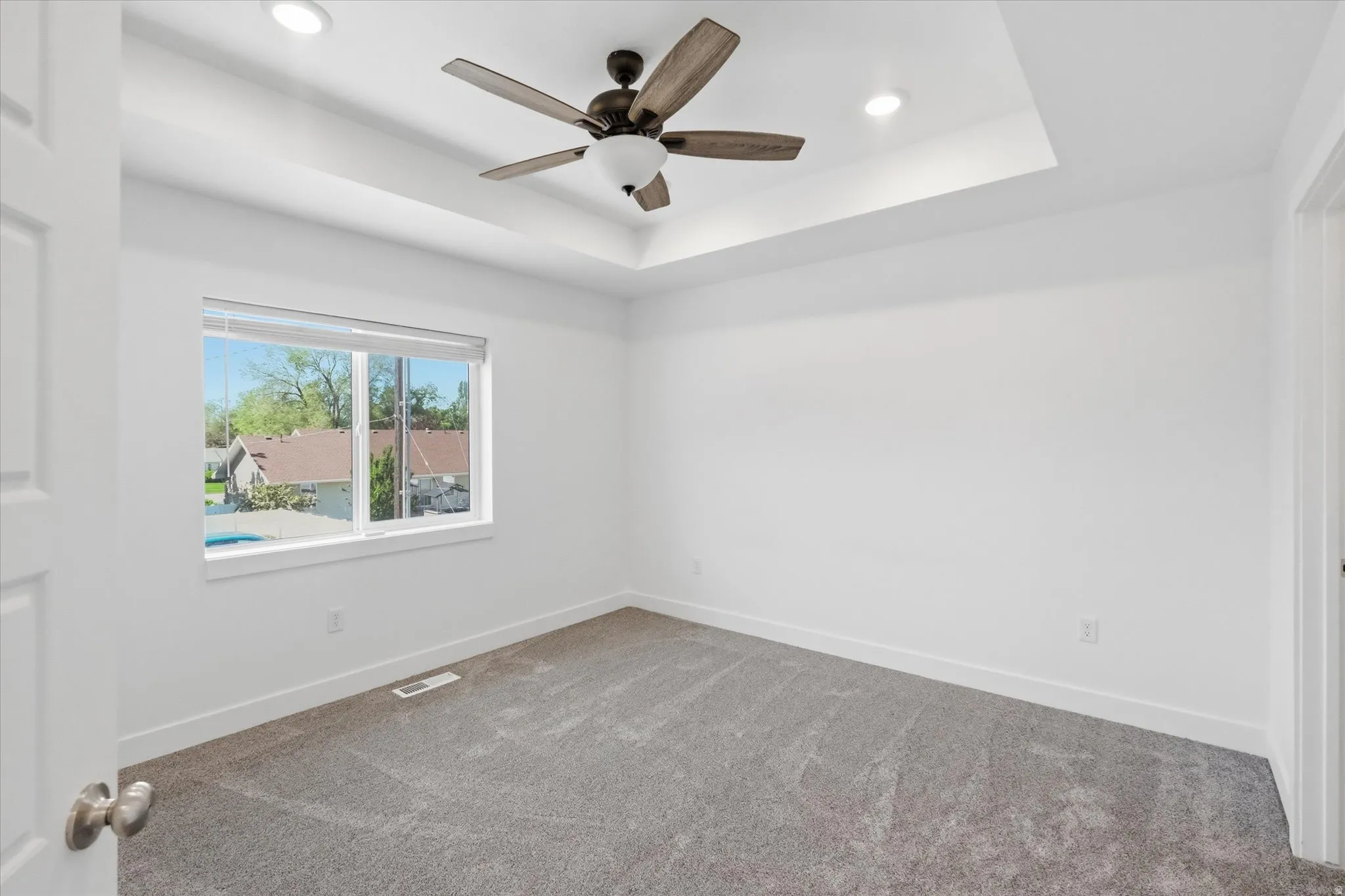 Recessed lighting illuminates a tray ceiling with a ceiling fan
