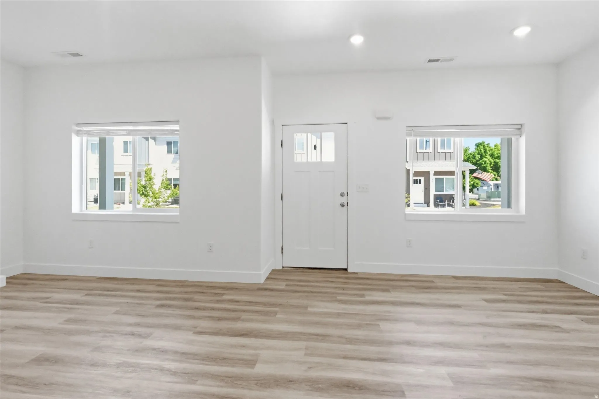 Spacious interior with wood-finish flooring, recessed lighting, and white walls