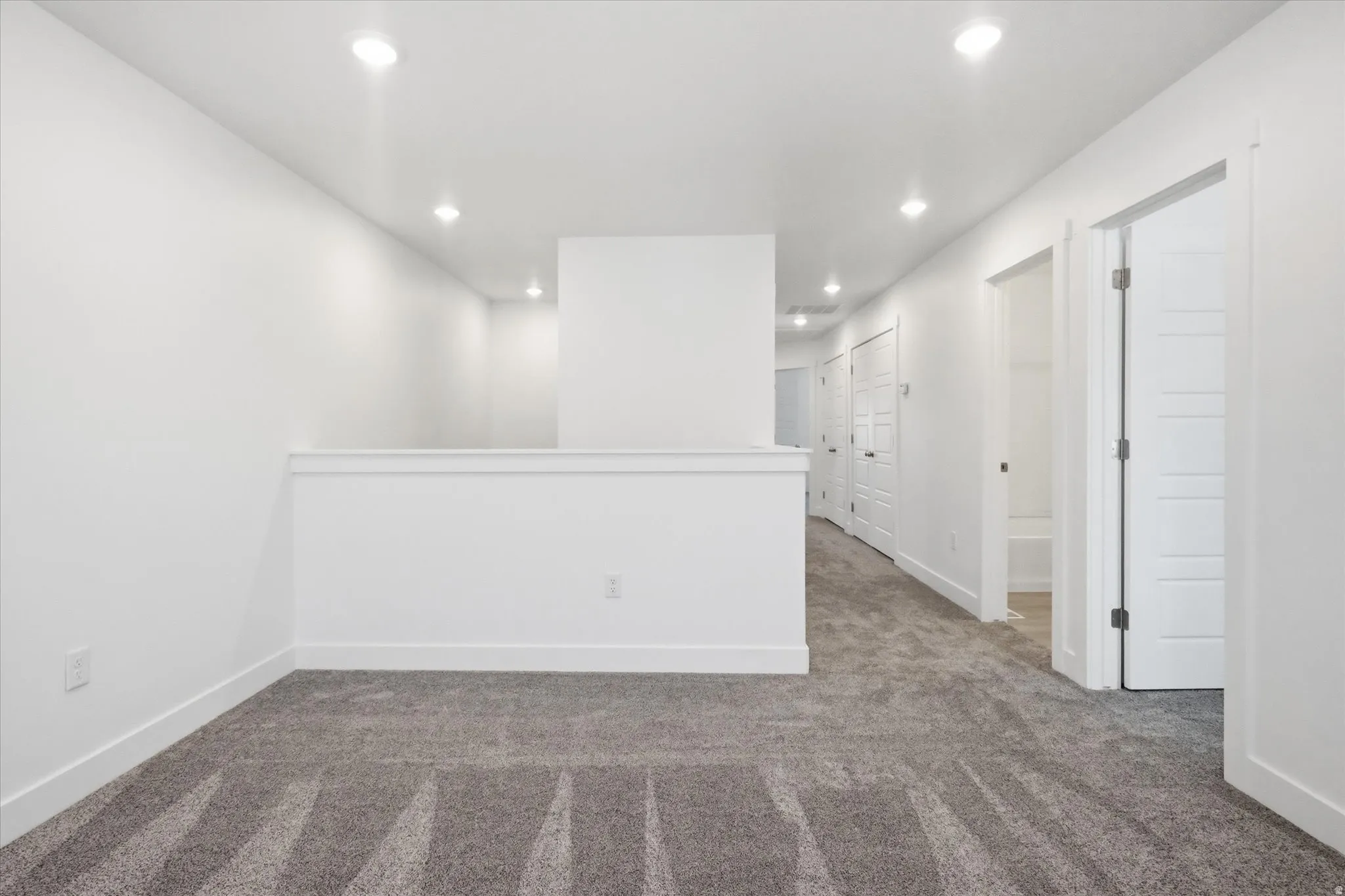 Carpeted loft area featuring recessed lighting