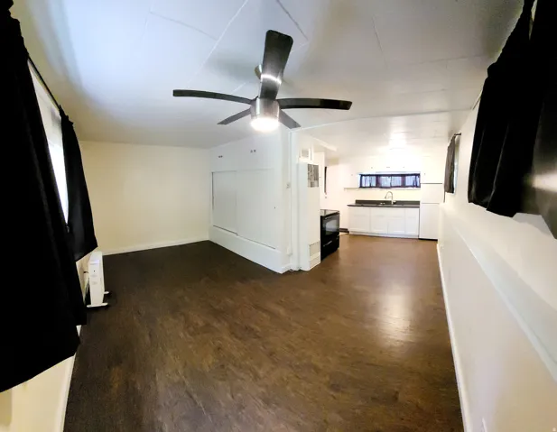 Open-concept living space featuring wood-finish flooring, a modern ceiling fan with lighting, and white walls