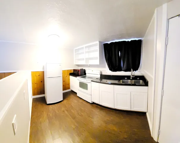 2nd Kitchen featuring white cabinetry, dark countertops, a double basin sink, and wood-finish flooring