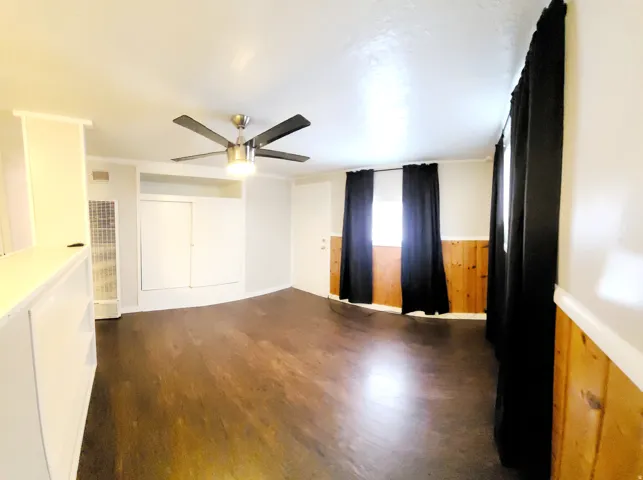2nd spacious bedroom featuring dark wood-finish flooring, a contemporary ceiling fan, and built-in cabinetry