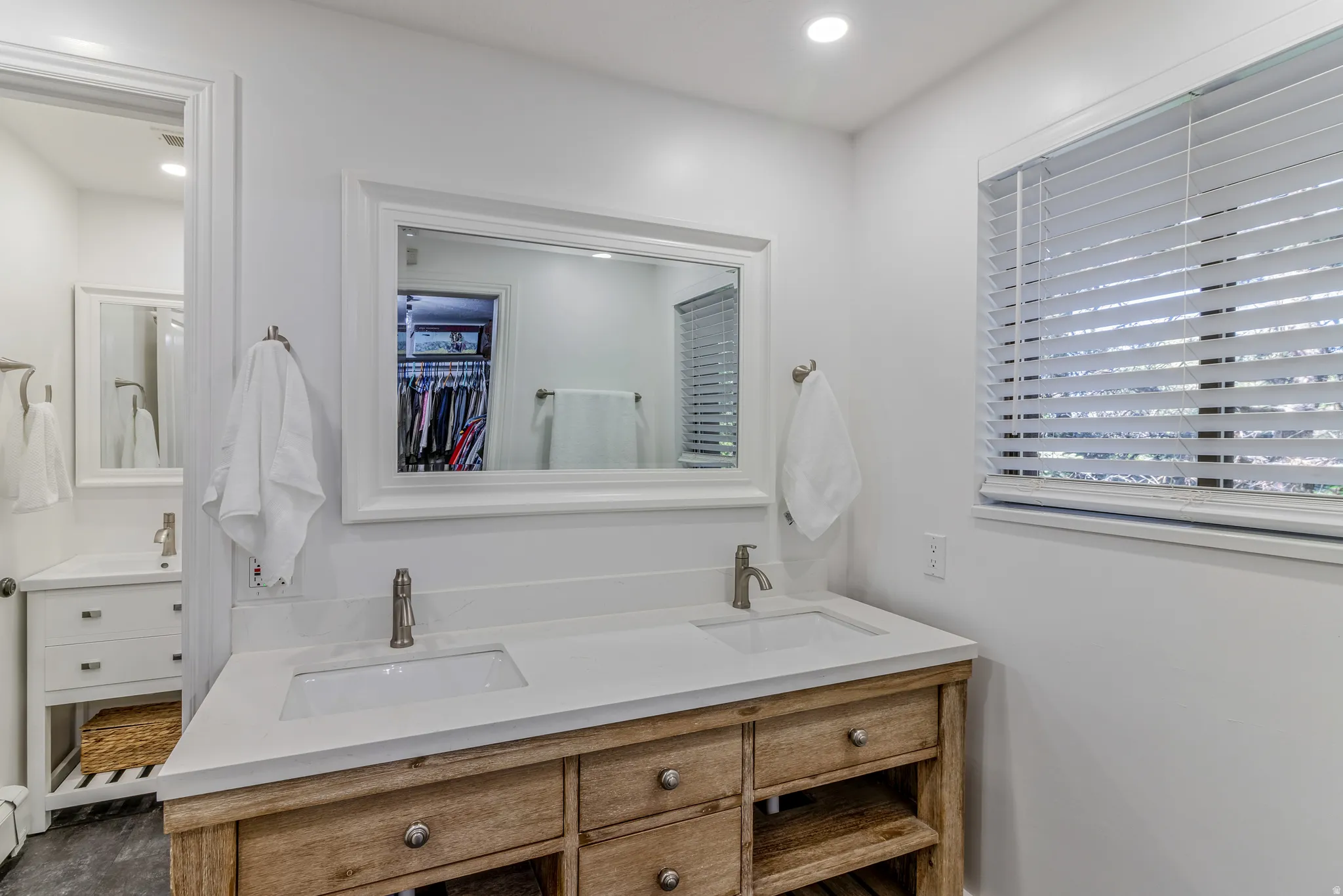 Bathroom featuring a dual-sink wood-finish vanity with stone-finish countertops