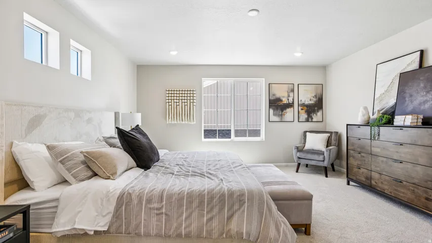 Spacious bedroom featuring light neutral wall tones, recessed lighting, and carpet flooring