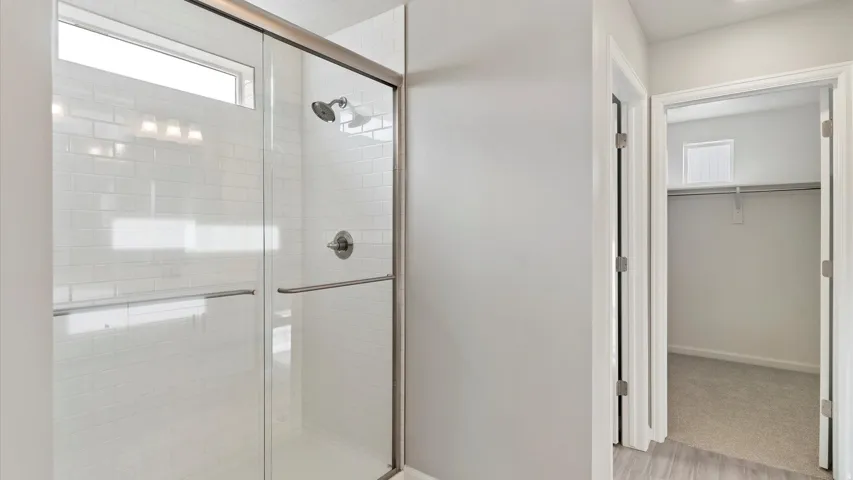 Spacious walk-in shower featuring subway tile surround, clear glass enclosure, and brushed nickel fixtures