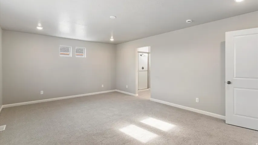 Spacious carpeted room featuring recessed lighting, two high windows, white trim, and a white paneled door