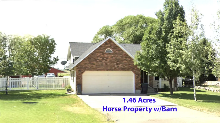 Brick-front residence featuring an integrated garage, asphalt driveway, and mature landscaping