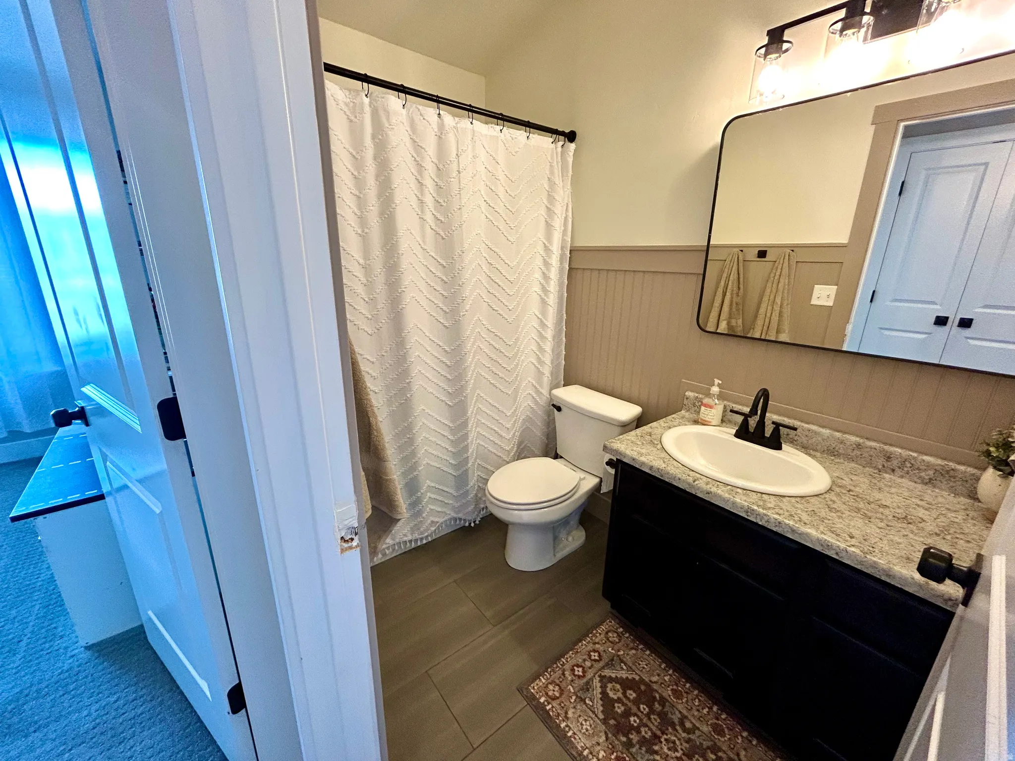 Bathroom featuring a dark wood vanity with a light speckled countertop, undermount sink, and matte black fixtures