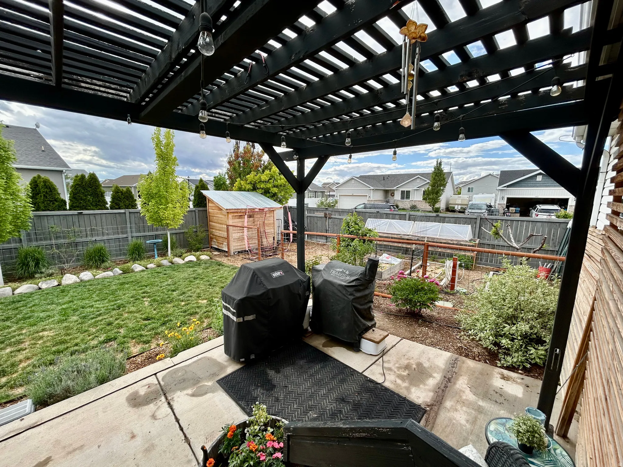 Patio with dark-stained wood pergola and string lighting