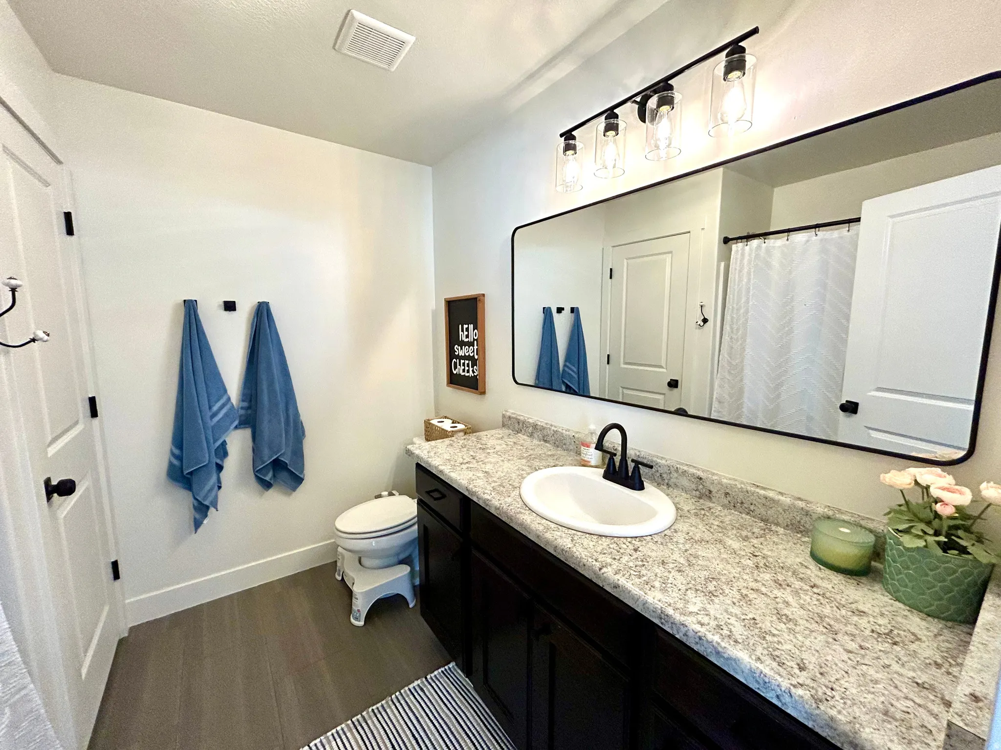 Bathroom featuring a dark wood-finish vanity with an integrated white sink, speckled countertop, and matte black faucet